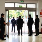 Emergency exit door with panic bar in a busy commercial building during a fire drill.